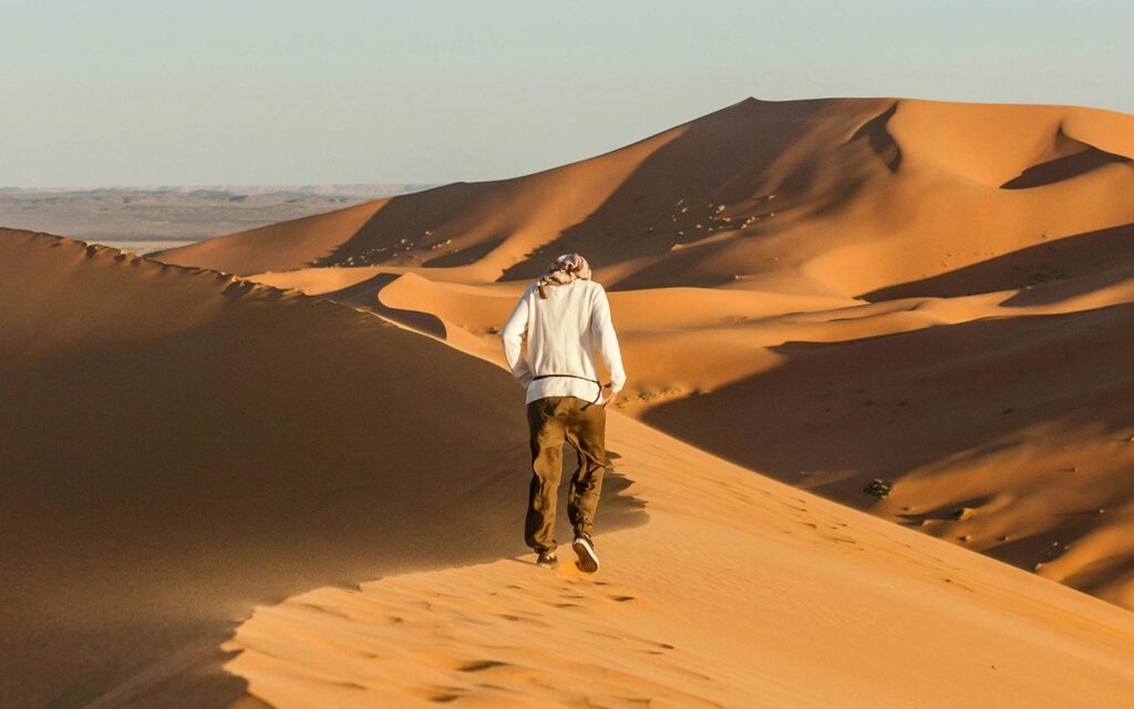 Man running across the desert of Erg Chebbi